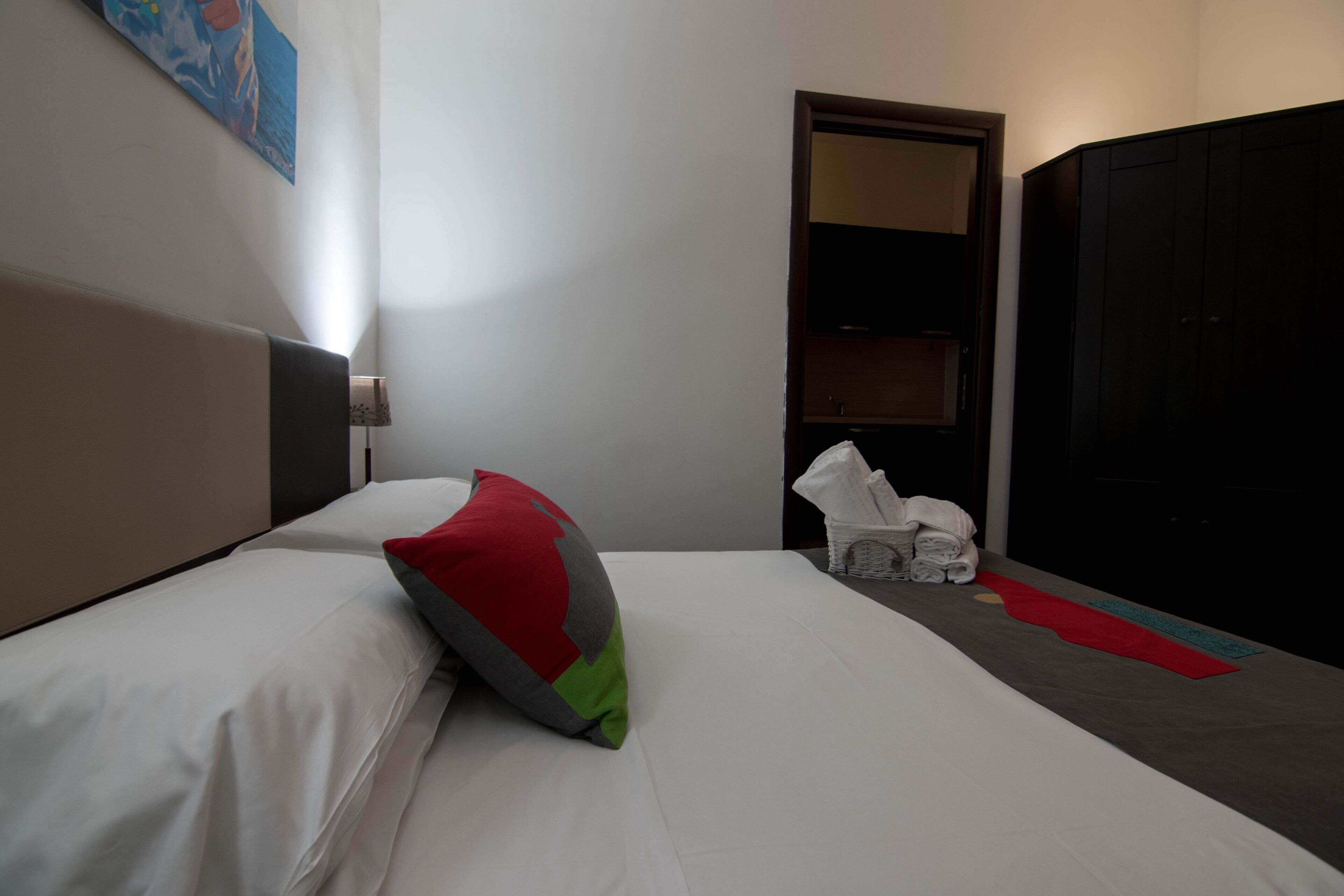 A hotel room with a bed, a nightstand, a wardrobe, and a painting on the wall.