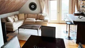 Un acogedor espacio tipo loft con una amplia sofa, una mesa de comedor y una original lámpara de astas.