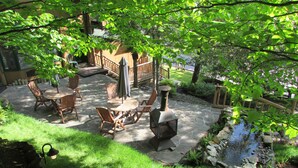 Un patio con suelo de piedra, muebles de madera y un pequeño estanque.