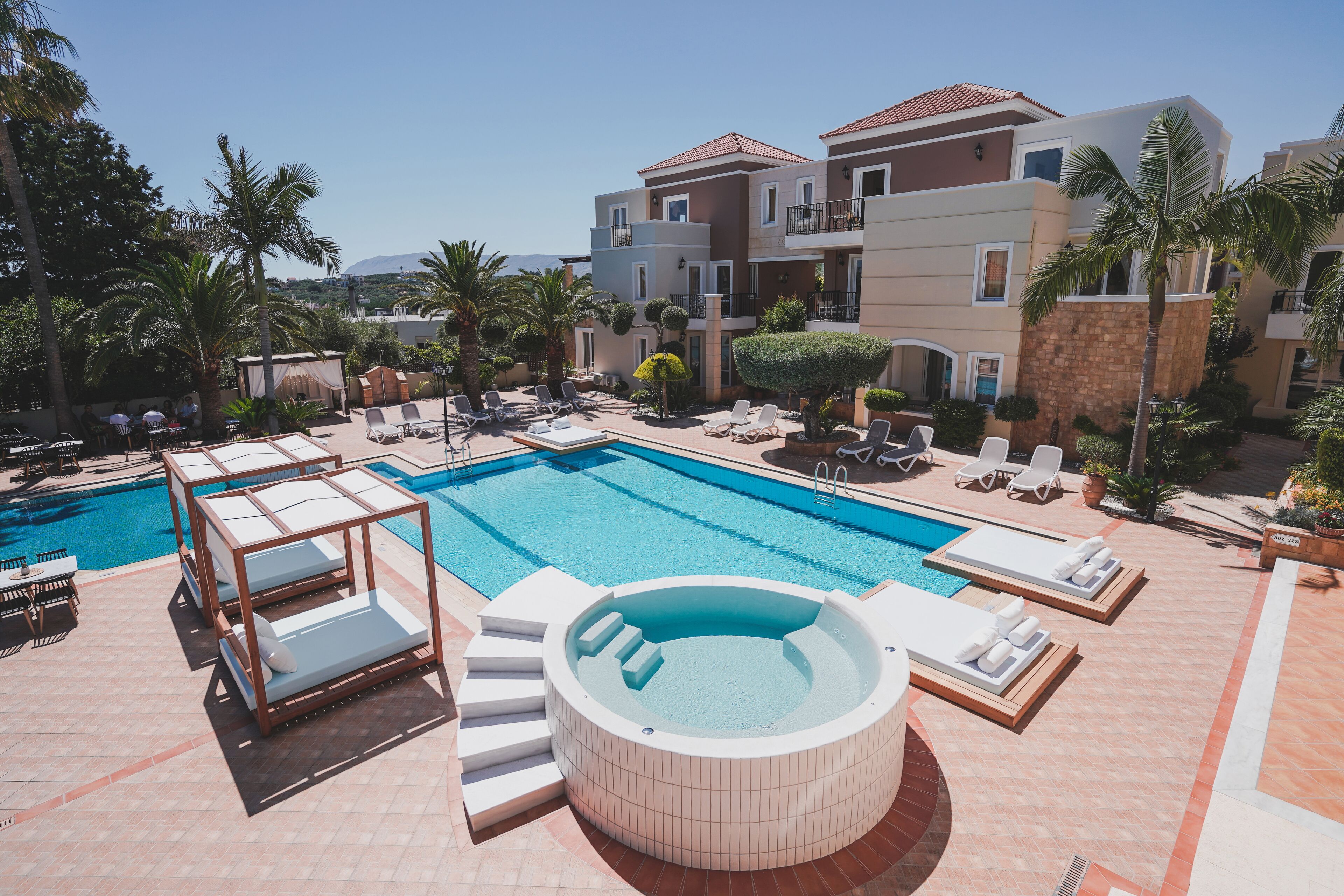 A pool area with lounge chairs, a hot tub, and a clear view of the surrounding buildings.