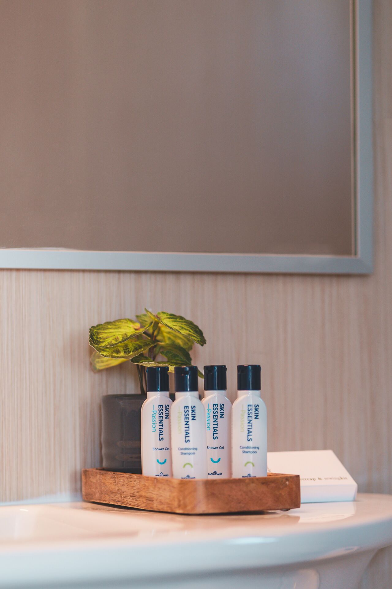 Un plateau en bois contenant quatre flacons de produits essentiels pour la peau, posé sur une étagère blanche.