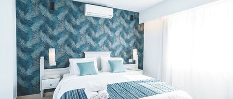 A modern bedroom with a large bed, white headboard, and a patterned wall.