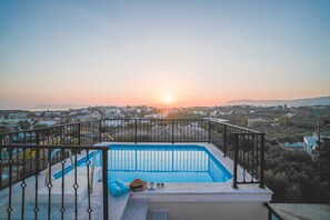 Une piscine sur le toit offrant une vue sur le paysage urbain au coucher du soleil.