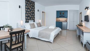 Habitación de hotel moderna con cama, escritorio, silla, kitchenette y baño.