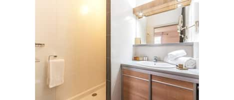 A modern bathroom with a shower, a sink, and a mirror.