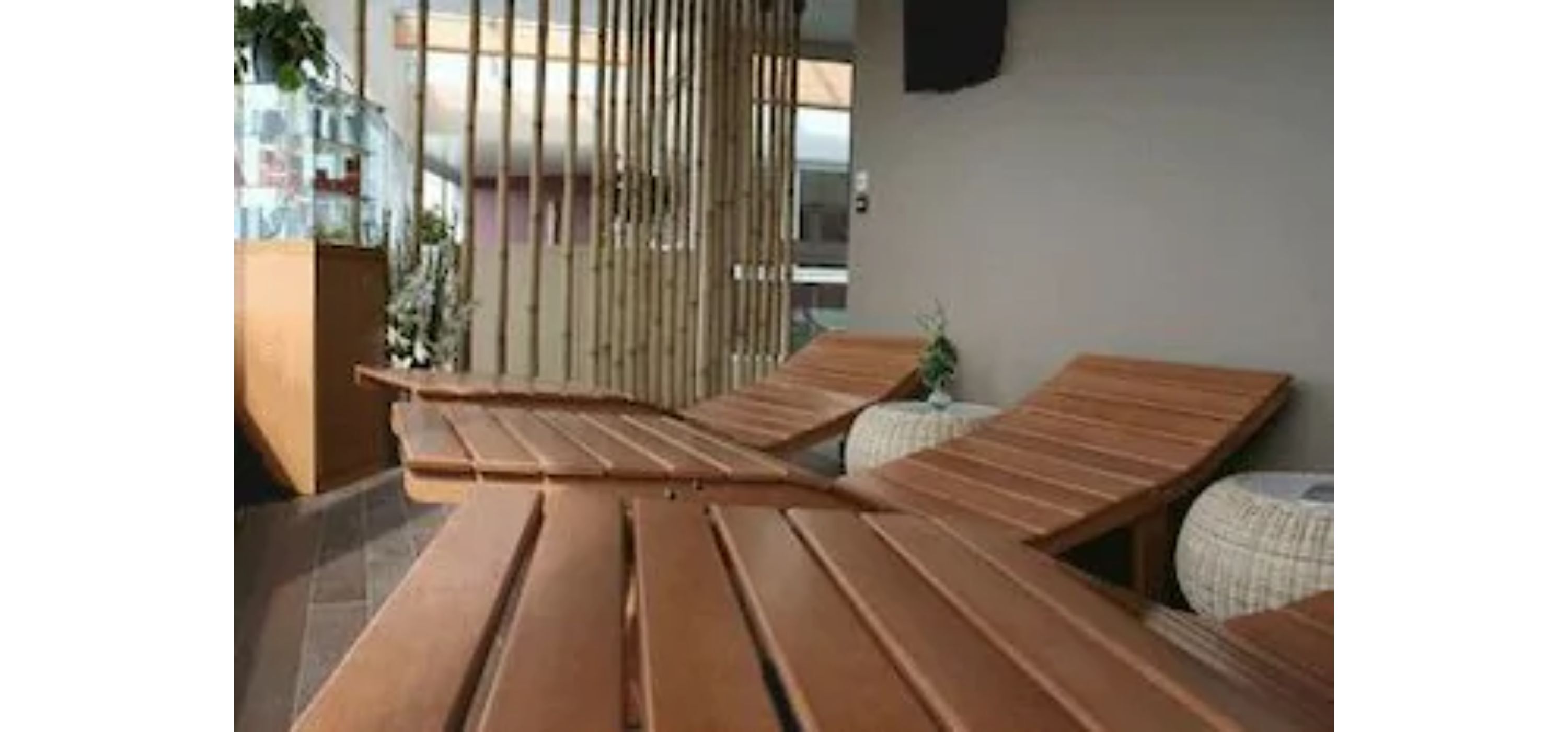 A modern lounge area with wooden benches and a bamboo screen.