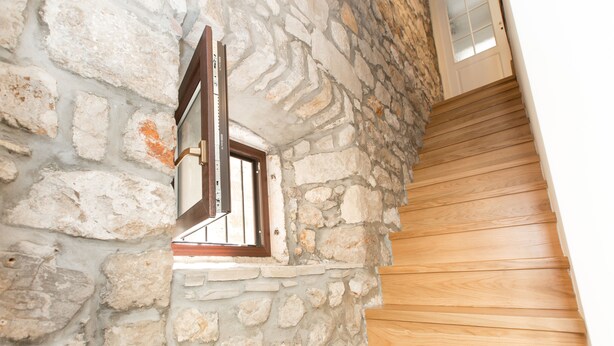 A stone wall with a window and wooden steps. - Apartments Santa Maria (Dubrovnik)