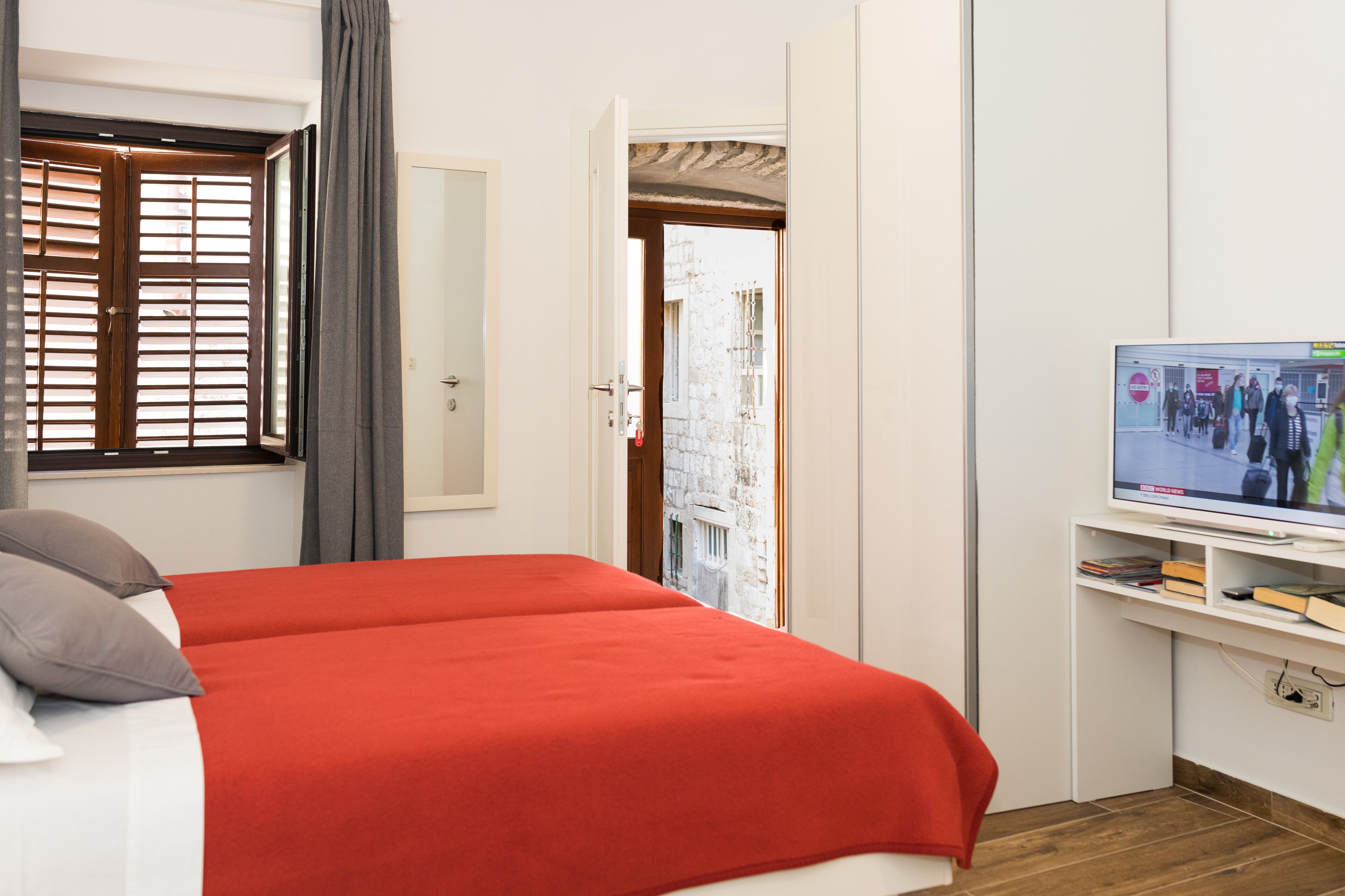 A hotel room with a bed, a television, and a door leading to a balcony.