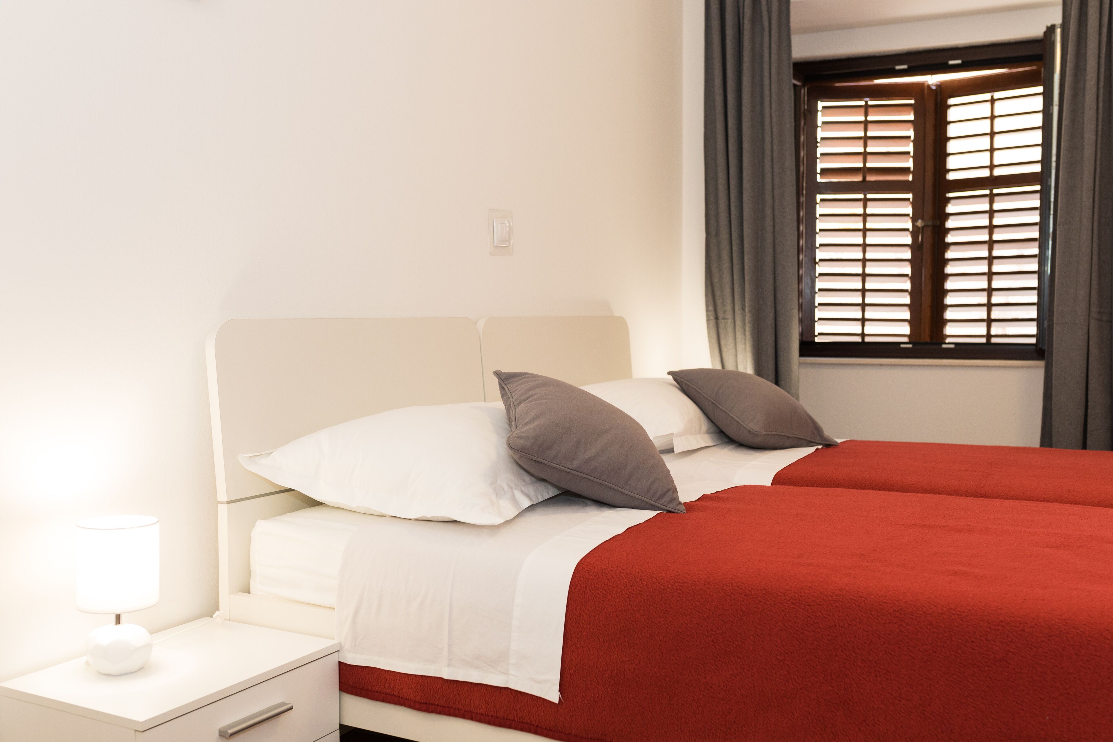 A hotel room with a bed, a nightstand with a lamp, and a window with curtains.