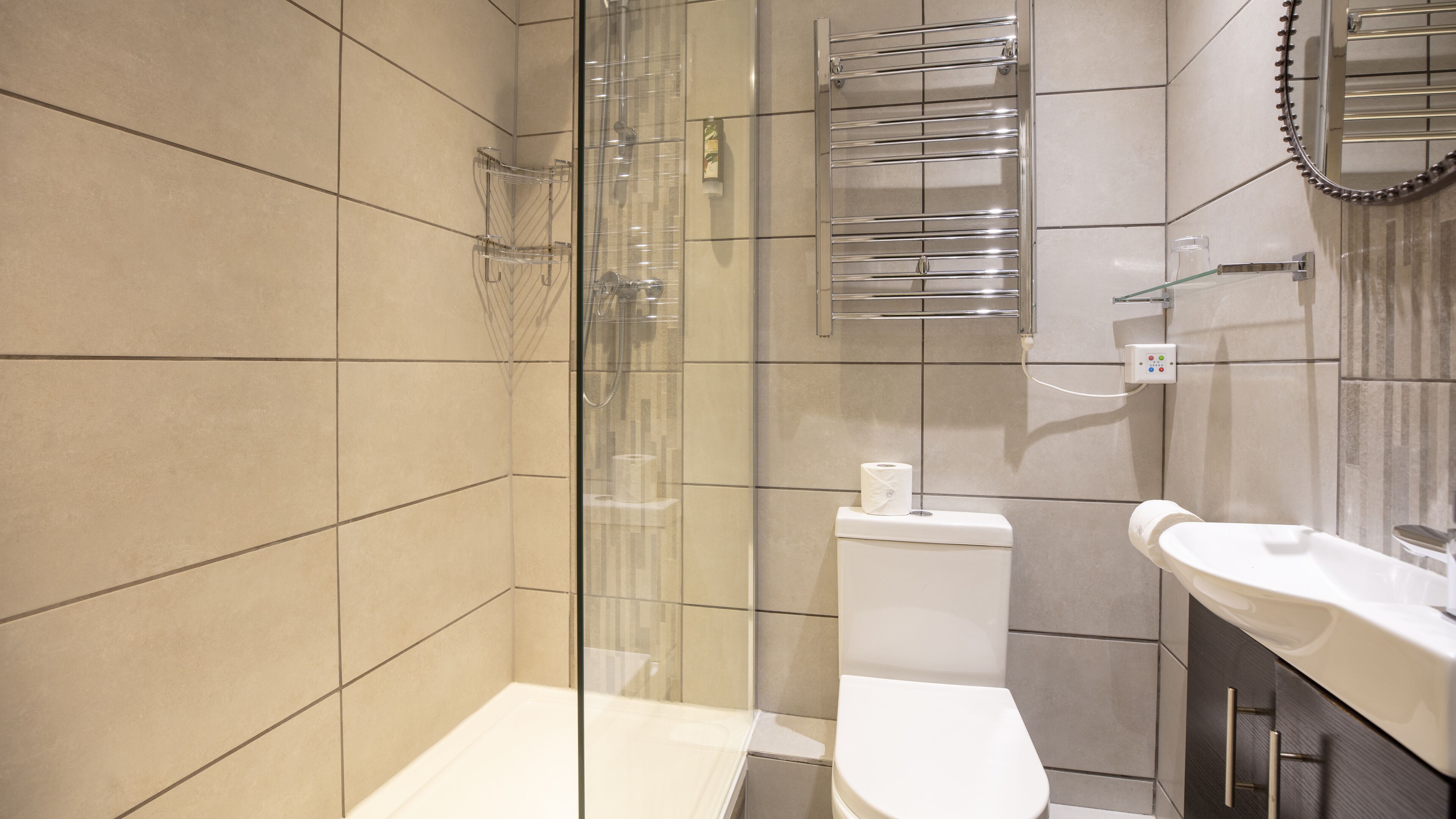 Een moderne badkamer met een douchecabine van glas, een toilet en een wastafel met spiegel erboven.