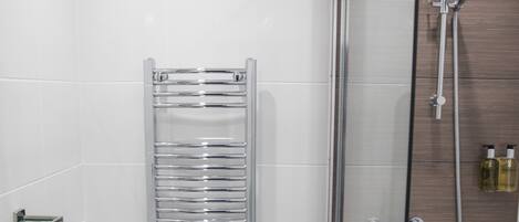 A modern bathroom with a glass-enclosed shower, a white toilet, and a chrome towel rack.