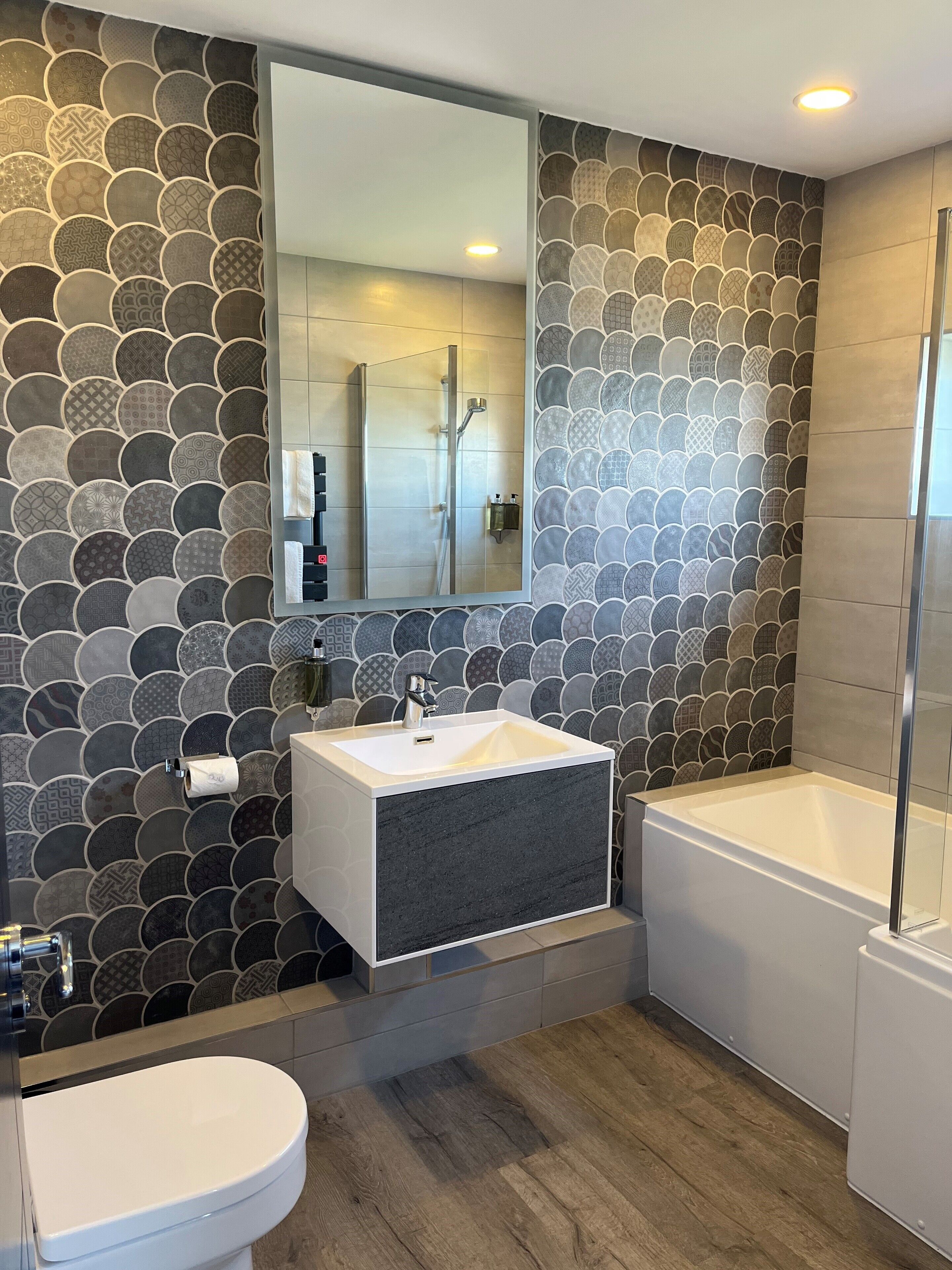 A modern bathroom with a stone-patterned wall, a white sink, a mirror, and a bathtub.