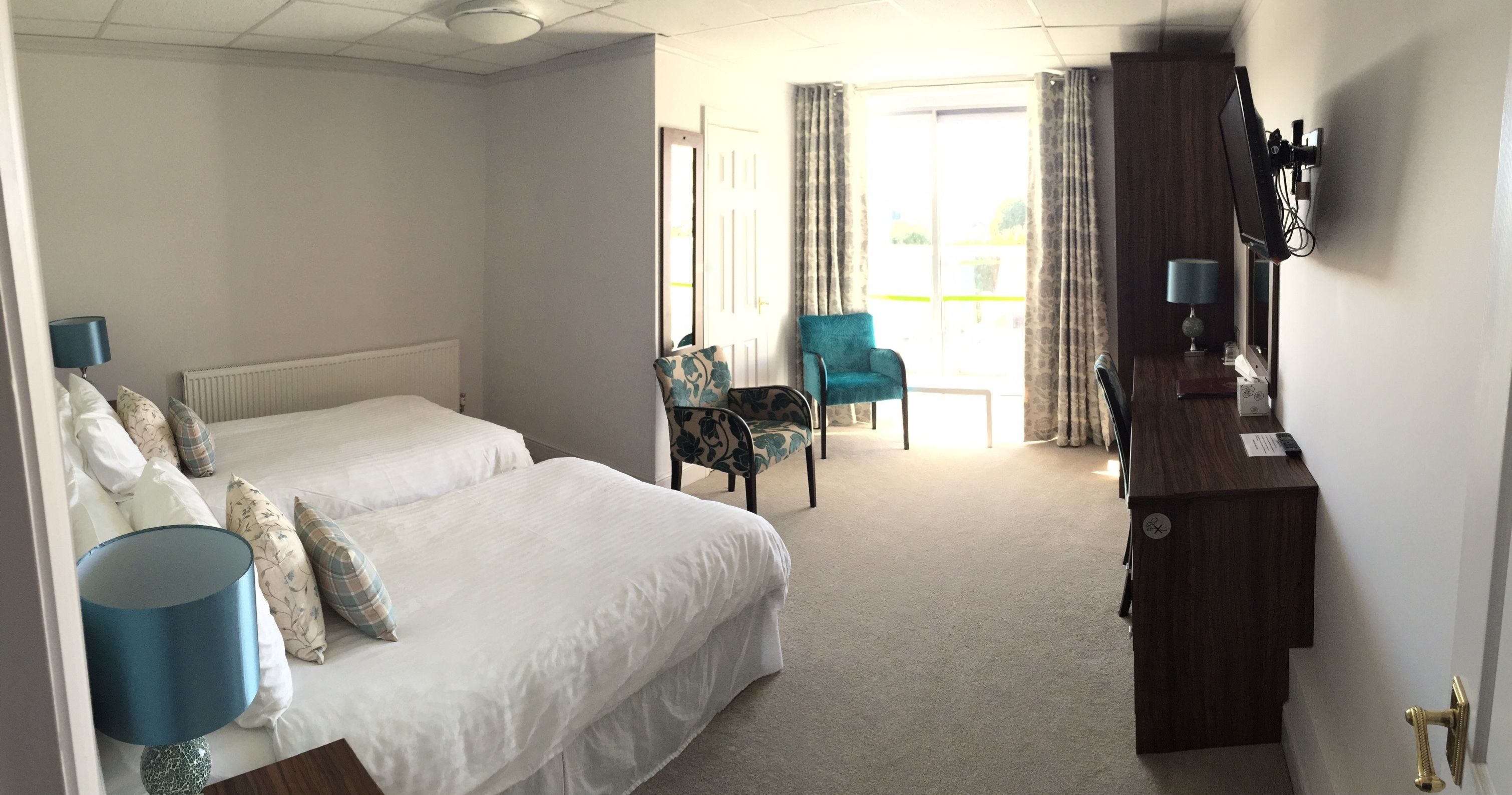Une chambre d’hôtel avec deux lits, un bureau, une chaise, une télévision et une vue sur l’extérieur.