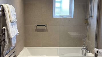 Une salle de bain moderne équipée d’une baignoire, de toilettes et d’une douche.