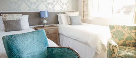 Une chambre d’hôtel avec un lit, une chaise, une table de chevet et une lampe.