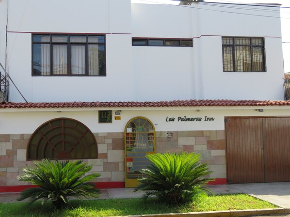 Un bâtiment à deux étages sur lequel on peut lire l’inscription « Las Palmeras Inn ».