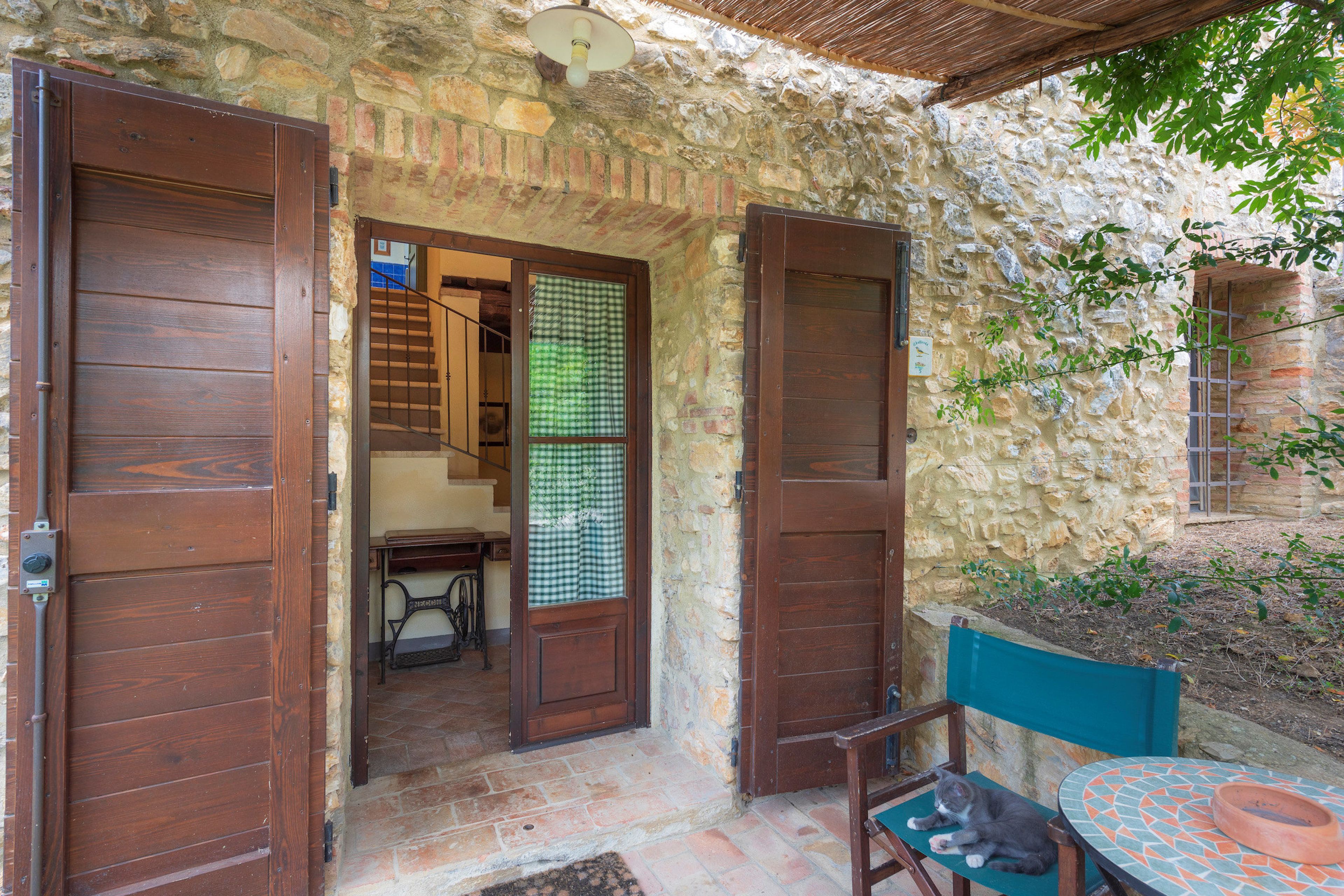 A stone building with wooden doors and a small patio area with a table and chair.