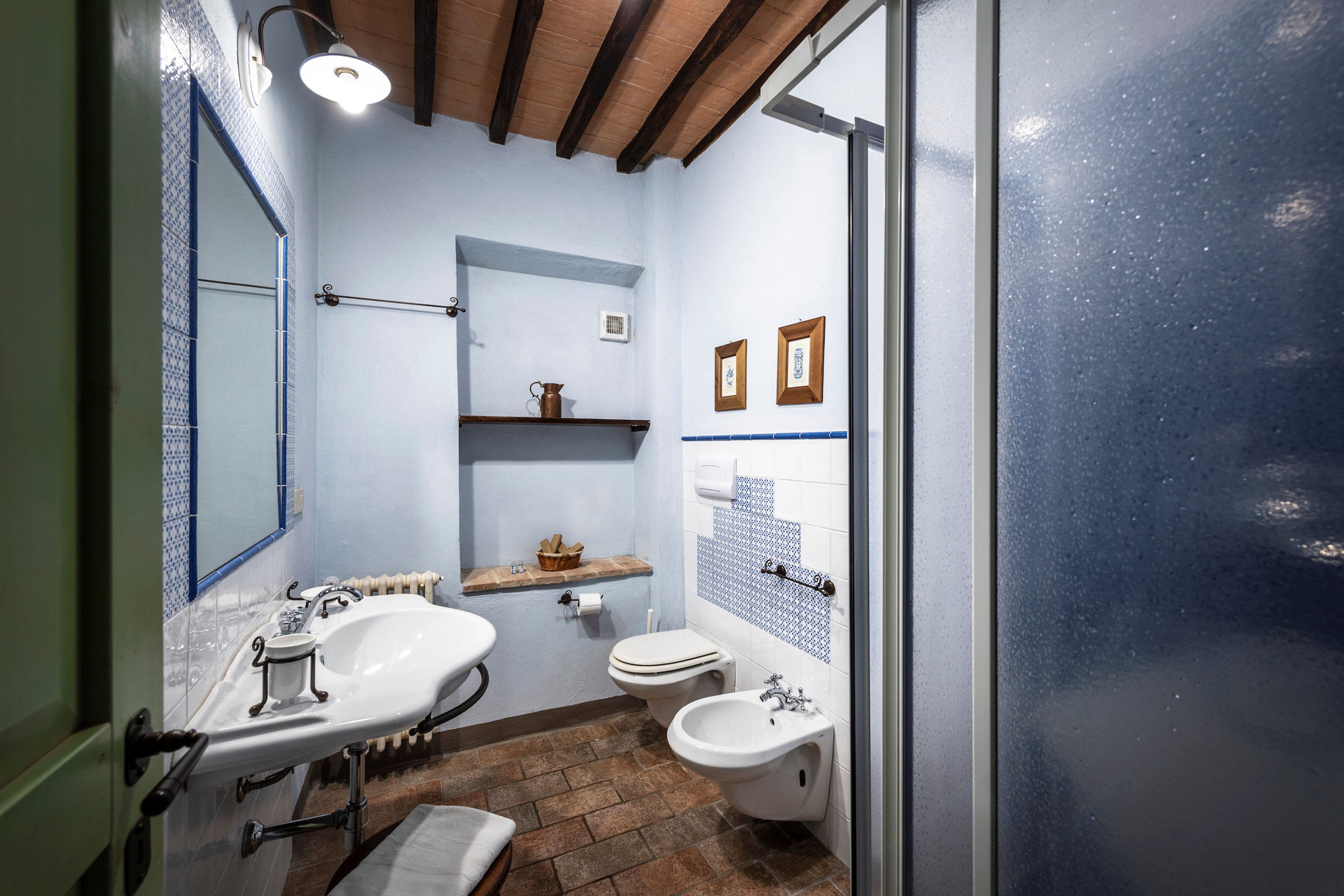 Een badkamer met een wastafel, twee kommen, een toilet en een bidet. Boven het toilet bevindt zich een plank en aan de muur hangt een spiegel.