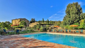 A swimming pool with tiled flooring, lounge chairs, and umbrellas. - Le Mascie Country House (Casole d'Elsa)