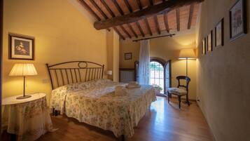 Un dormitorio con cama, una silla, una mesa con lámpara y una ventana que ofrece vistas al exterior.