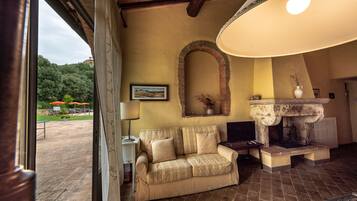 A cozy interior with a beige sofa, a stone fireplace, and a view of the outdoors.
