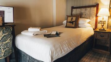 A neatly made bed with a pillow featuring an eagle design, a bedside lamp, and a framed menu on the nightstand.
