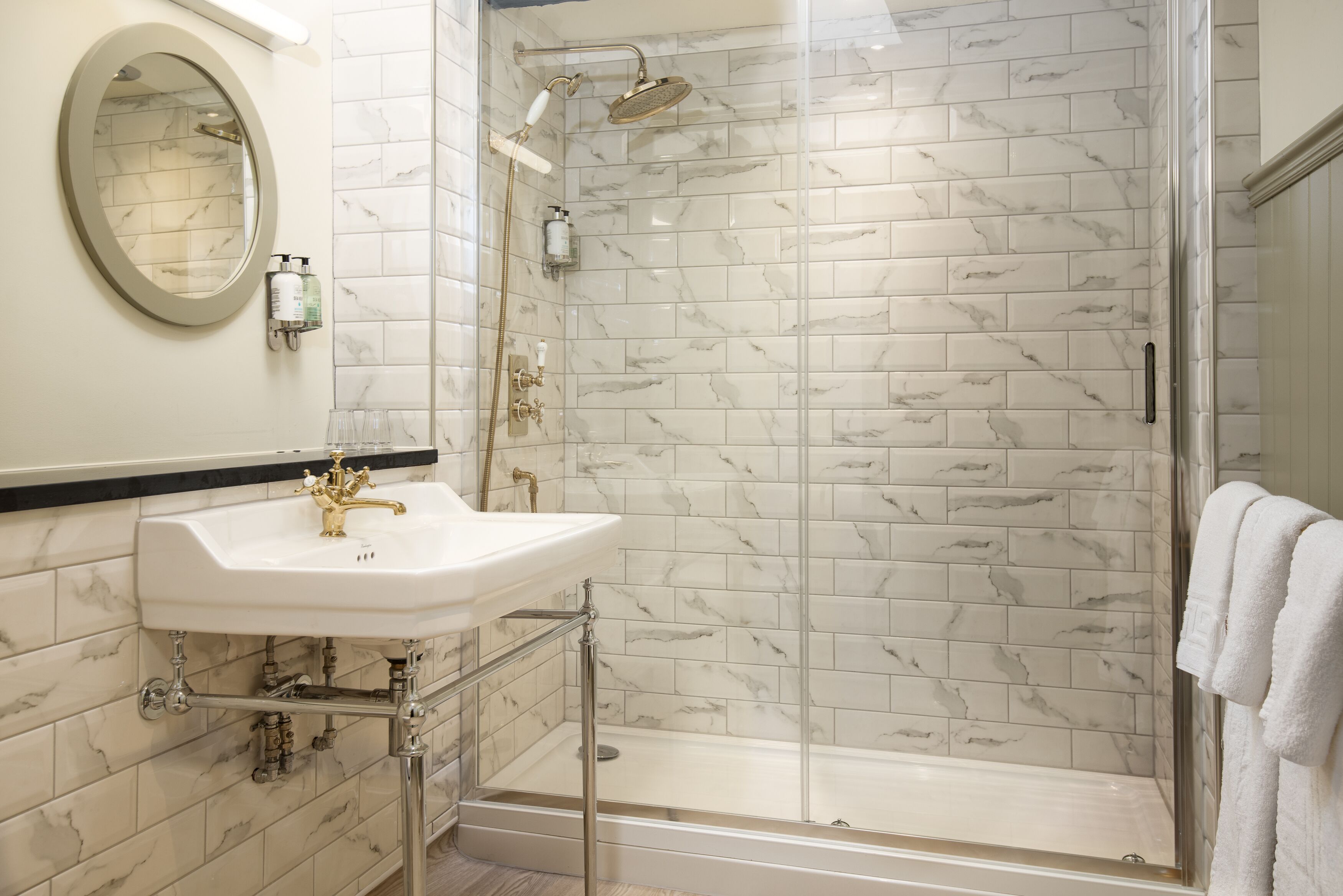Een badkamer met wastafel, spiegel en douche.