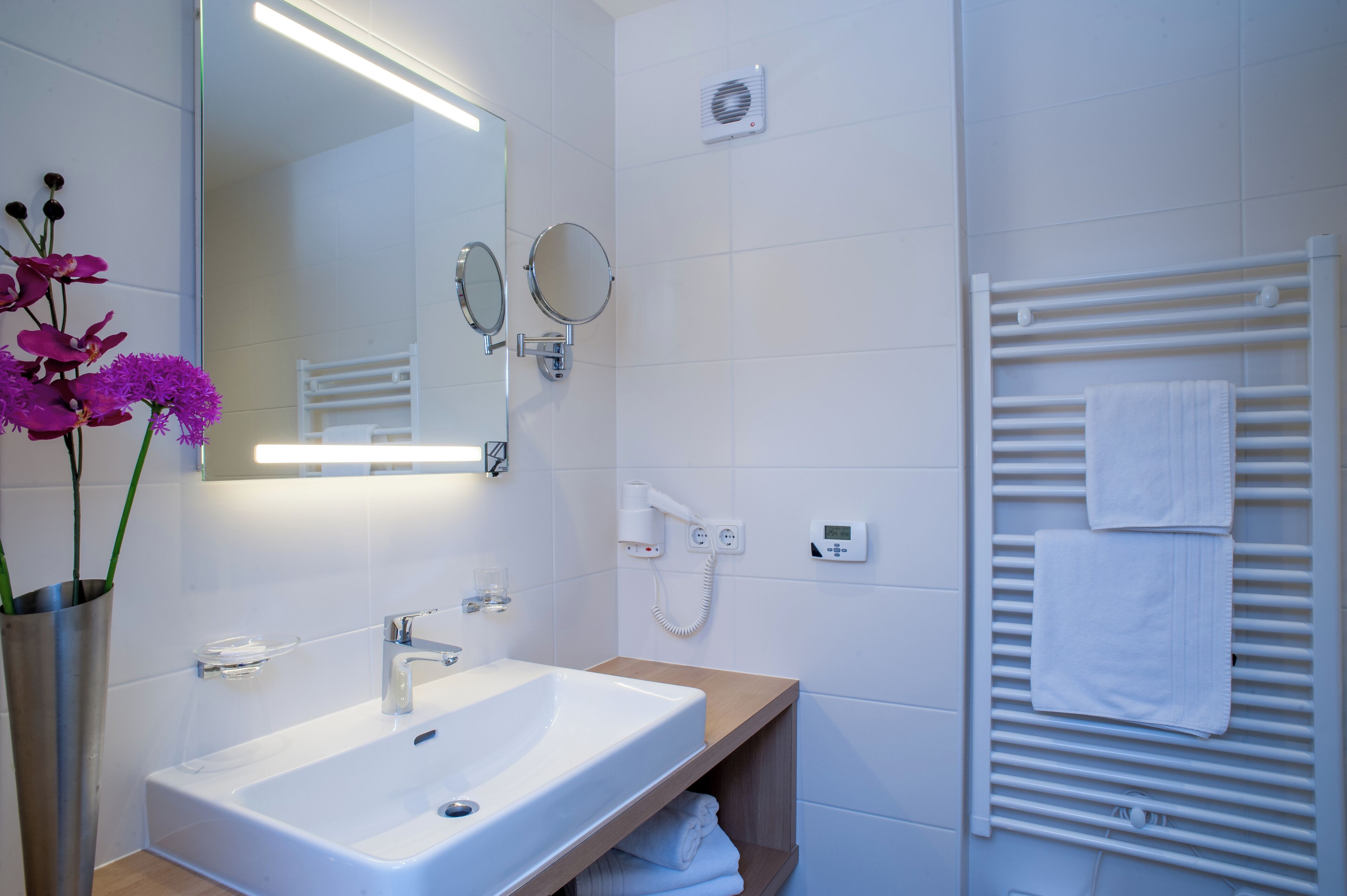 Un bagno moderno con lavandino, specchio e porta asciugamani bianchi.