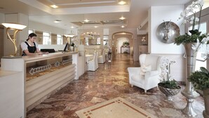 A hotel lobby with a reception desk, seating area, and decorative elements like a star ceiling and potted plants. - Hotel Rumer Hof (Rum)