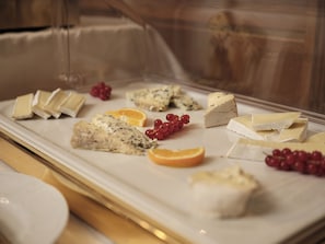 A cheese display with various types of cheese and fruits.
