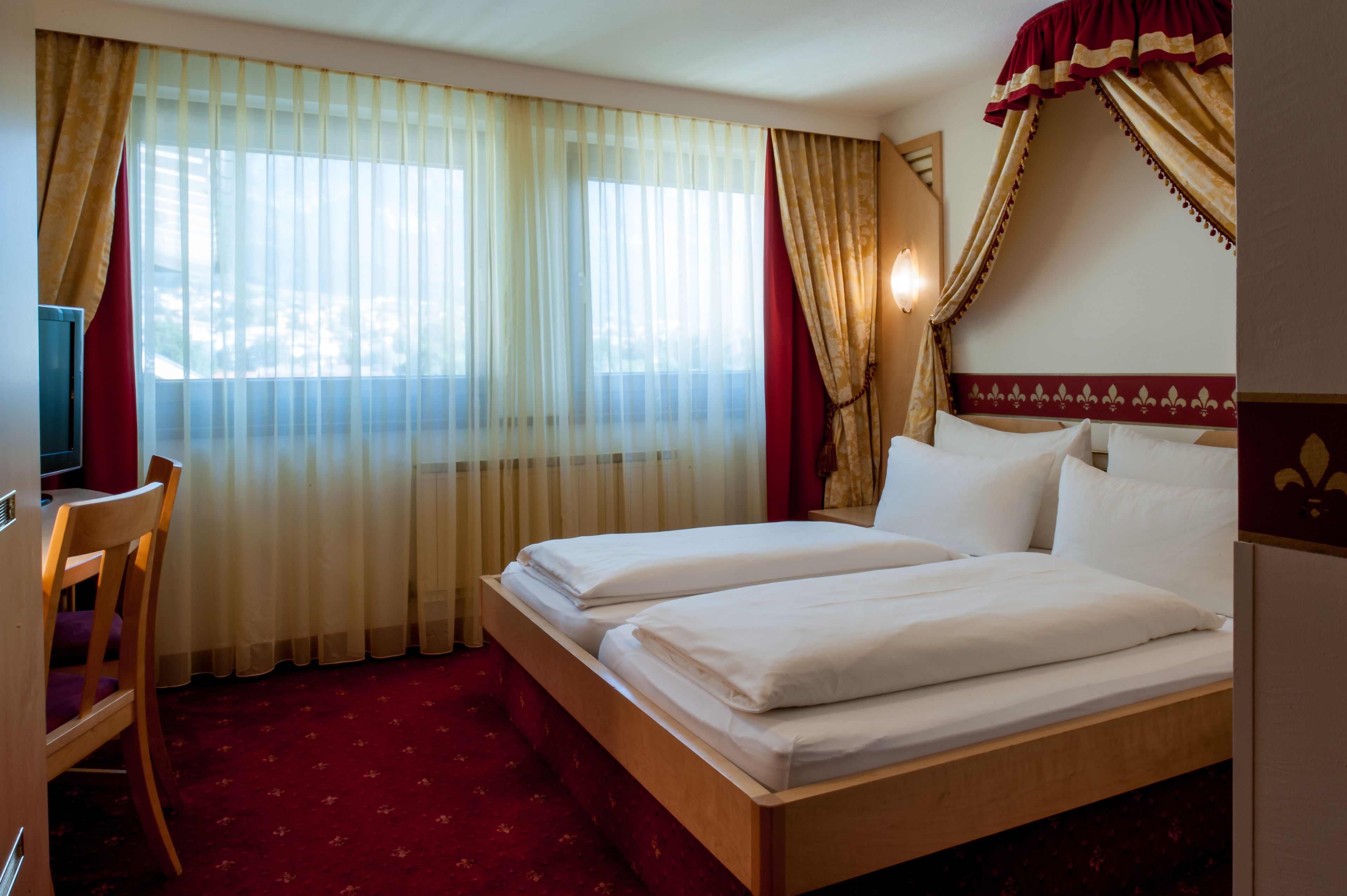 A hotel room with a bed, a desk, and a chair.