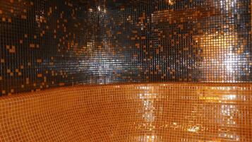 A room with a reflective, mosaic-tiled floor and walls, creating a vibrant, shimmering effect.