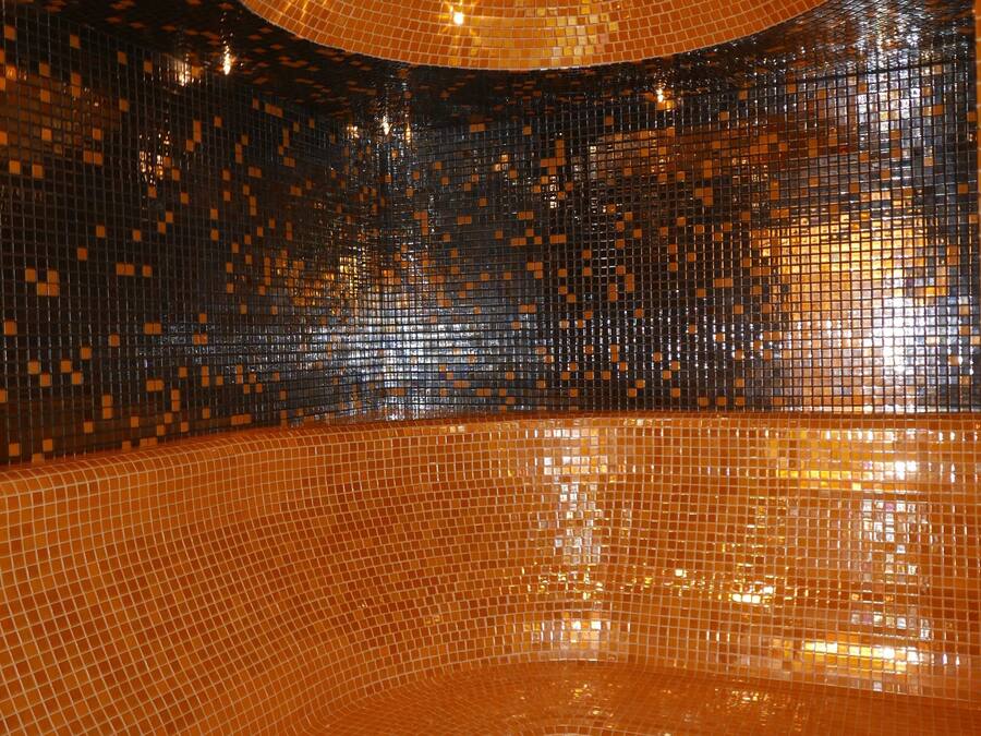 A room with a reflective, mosaic-tiled floor and walls, creating a vibrant, shimmering effect.