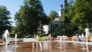 A public square with a central fountain, benches, and a church in the background. - Rezydencja Grawert - Victorian Boutique & SPA (Ladek-Zdroj)