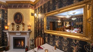 A dining room with a fireplace, ornate wallpaper, and a large mirror. - Rezydencja Grawert - Victorian Boutique & SPA (Ladek-Zdroj)