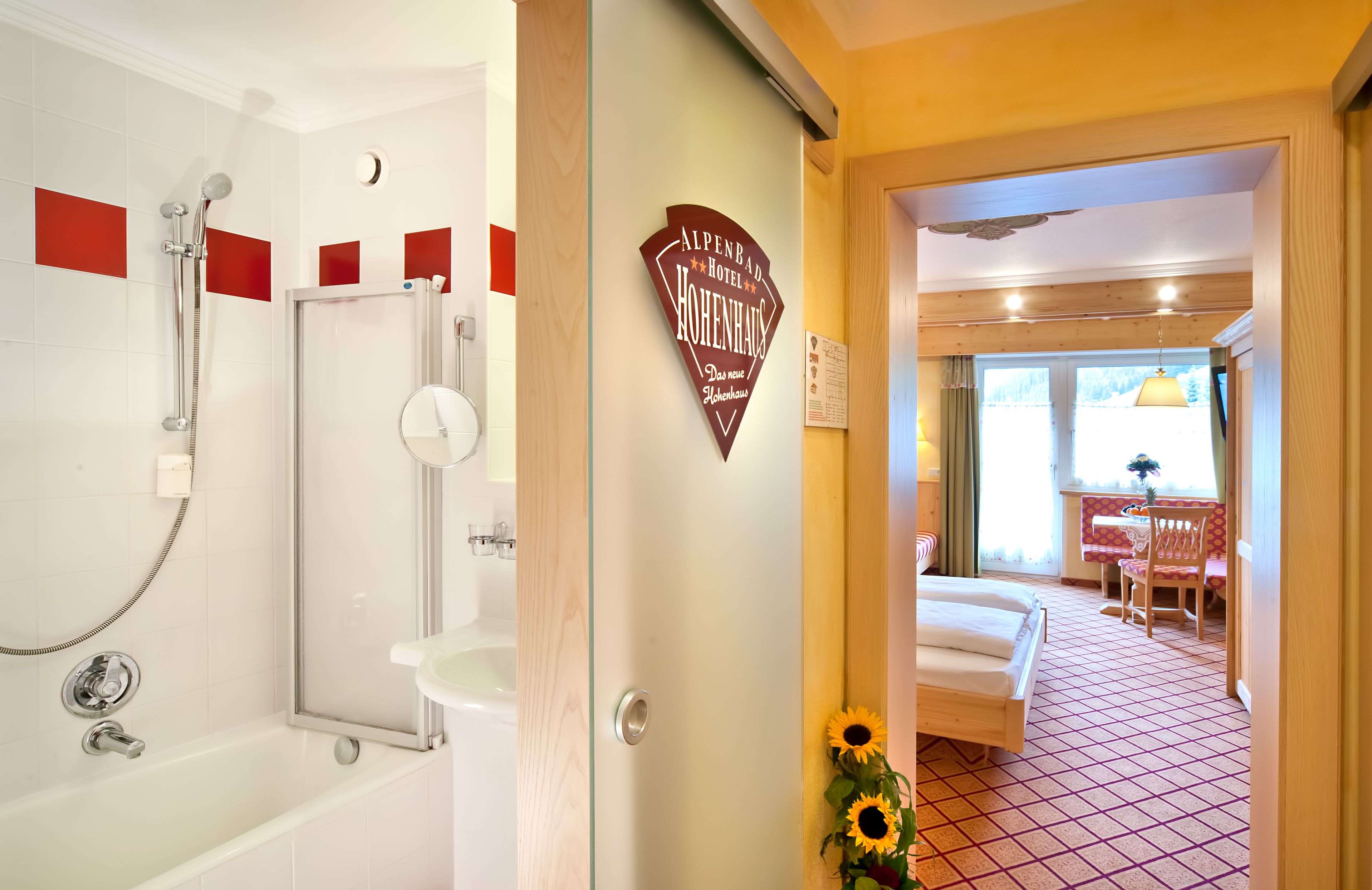 Habitación de hotel con ducha, cama, una mesita con silla y ventana con vistas al exterior.