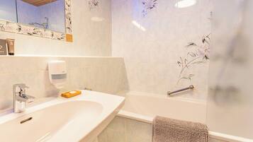 Un baño con lavabo, espejo, dispensador de jabón y bañera.