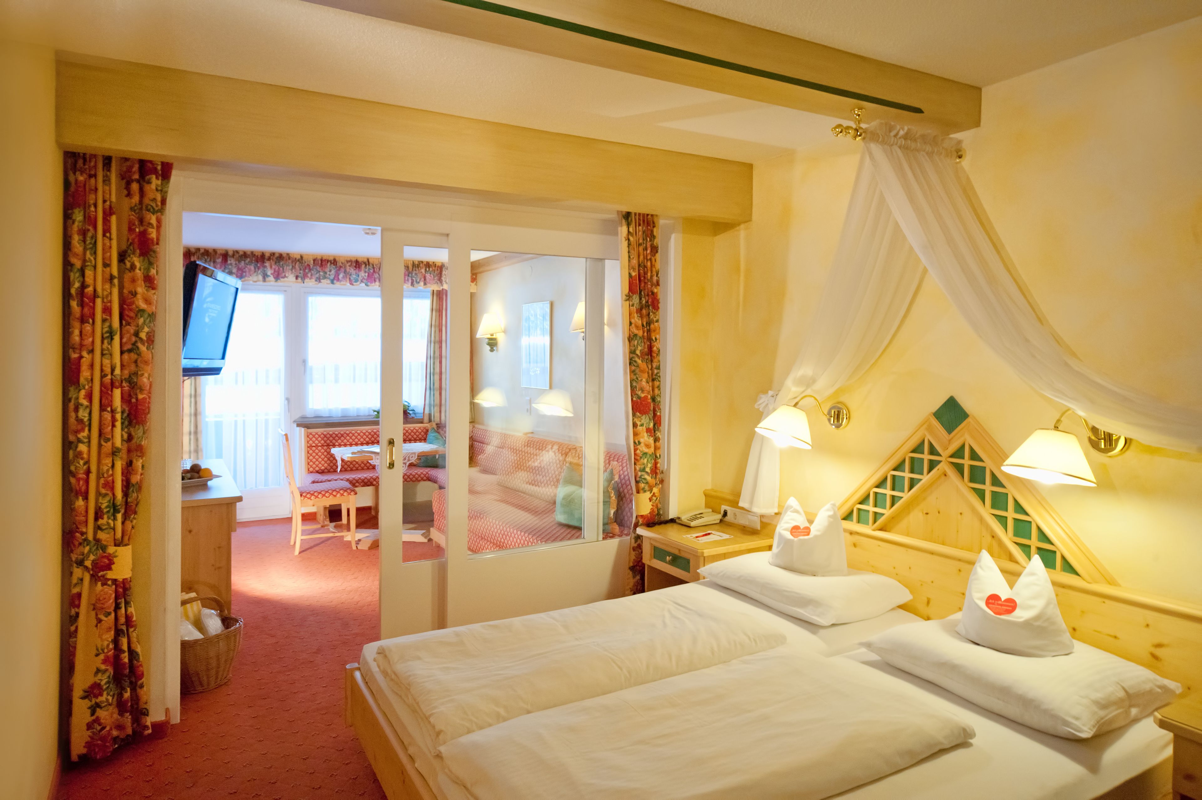 A hotel room with a bed, bedside tables, a desk, a chair, and a television.