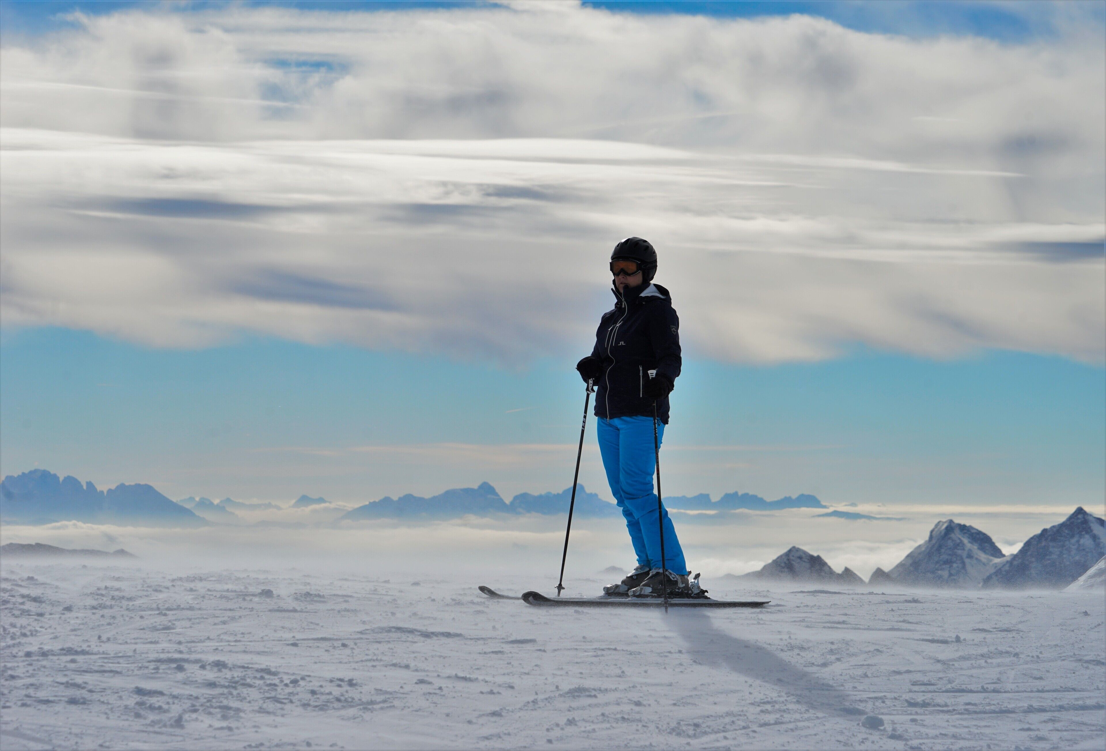 A person skiing on a snowy mountain with a clear sky and distant mountains.