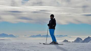 A person skiing on a snowy mountain with a clear sky and distant mountains.