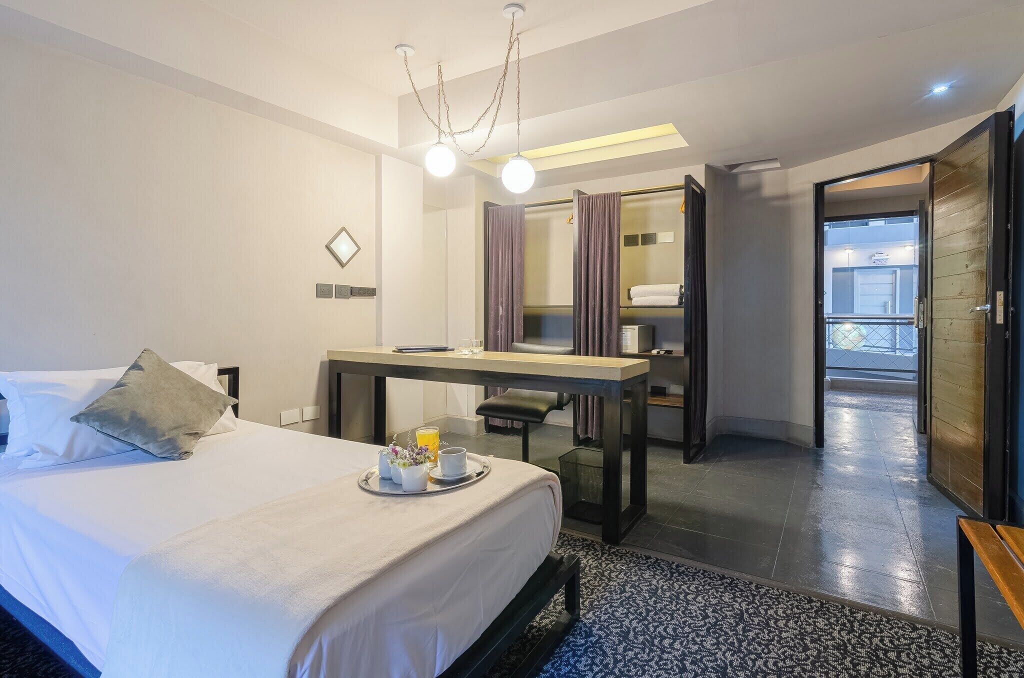 A hotel room with a bed, a desk, a mirror, and a bathroom door.