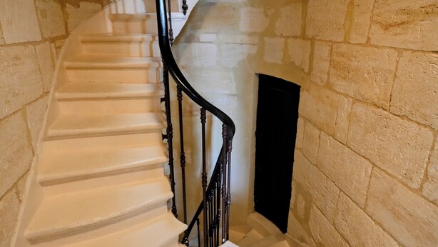 A spiral staircase with white steps and black balusters, leading to a landing with a black door. - Au cœur de Bordeaux B&B (Bordeaux)