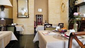 A dining area with tables set for meals, a mirror on the wall, and a vintage-style lamp. - Au cœur de Bordeaux B&B (Bordeaux)