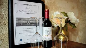 A framed welcome sign with a building illustration, a bottle of La Freyella wine, and two wine glasses on a wooden table.