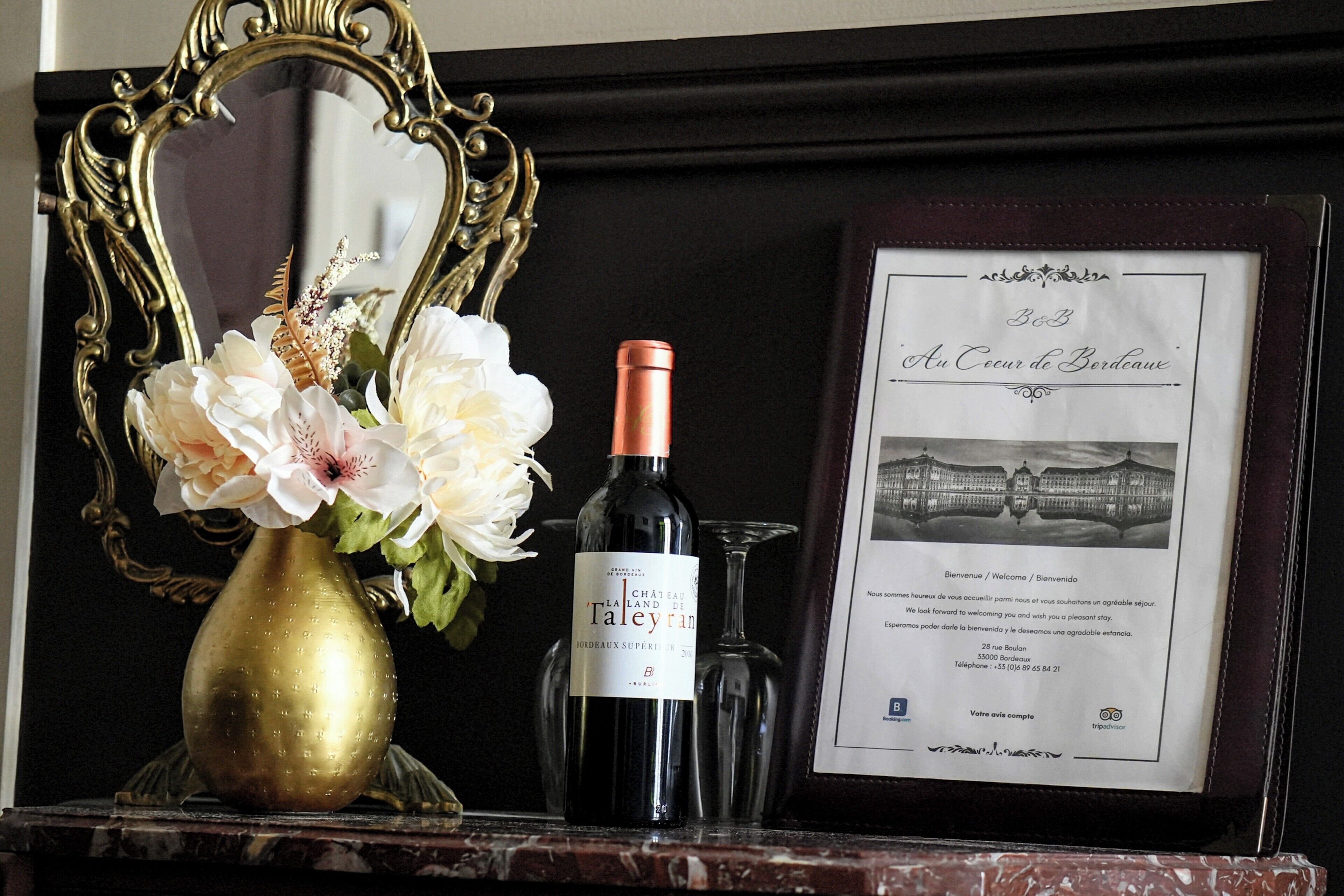 Un certificat encadré, une bouteille de vin et un vase rempli de fleurs, le tout posé sur une surface en marbre.