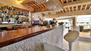 Un espace bar avec un mur en pierre, un plafond en bois et une variété de bouteilles et de verres.