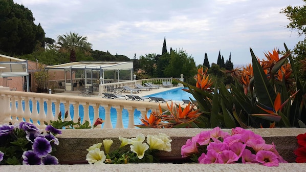 Zona de piscina con sillones de descanso y un espacio de estar techado.