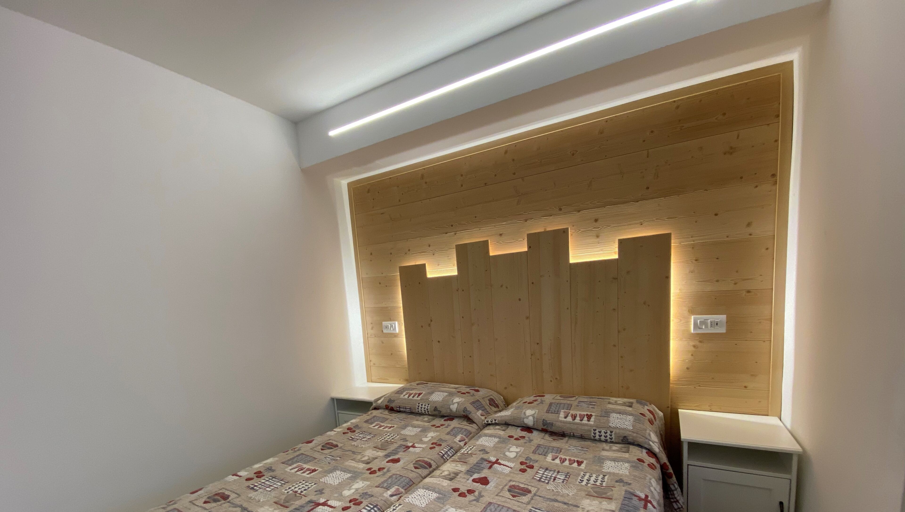 A bedroom with a wooden headboard, a patterned bedspread, and bedside tables.