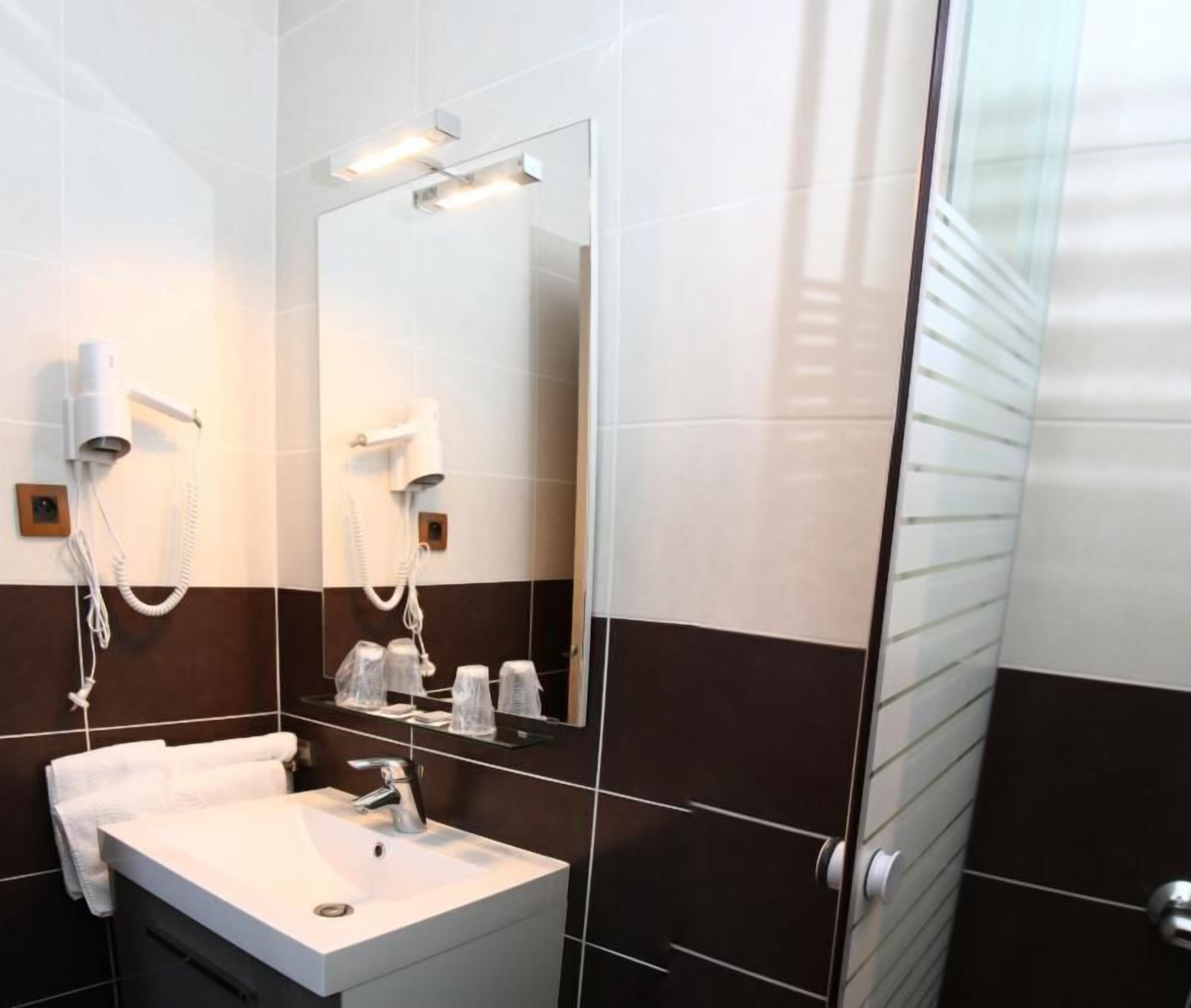 Un baño moderno con un lavabo blanco, un secador de pelo y un espejo.