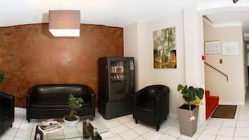 A spacious living area with a black leather sofa, a coffee table, and a fireplace. There are potted plants and artwork on the walls.